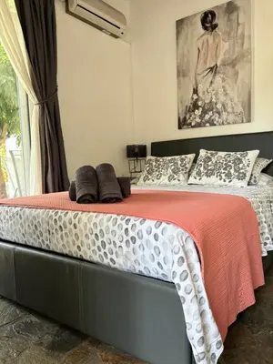 a bedroom with a bed with a red and white comforter at Mediterranean poolside garden cottage in Kiti
