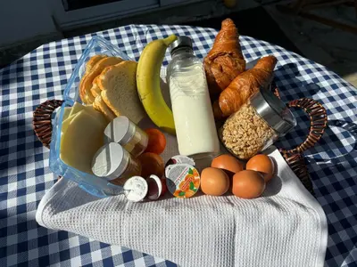 a picnic basket filled with breakfast foods and a bottle of milk at Mediterranean poolside garden cottage in Kiti