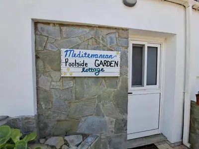 a building with a sign on a stone wall at Mediterranean poolside garden cottage in Kiti