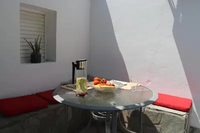 a table with a bowl of fruit on a balcony at Mediterranean poolside garden cottage in Kiti