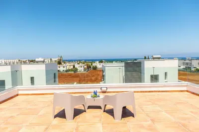 a patio with two white chairs and a table on a roof at Protaras Sol e Mar Villa 1 in Protaras