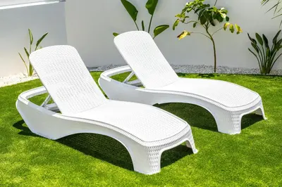 two white chairs sitting on the grass at Protaras Sol e Mar Villa 1 in Protaras
