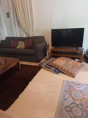 a living room with a couch and a flat screen tv at Glykoharama Cottage in Kalopanayiotis