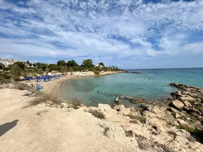 a beach with people swimming in the water at Villa Katia in Protaras