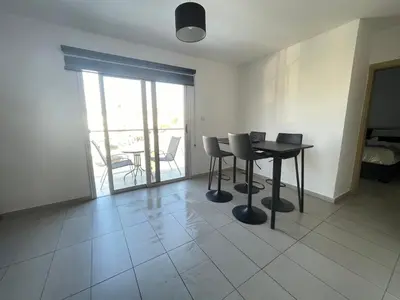 a dining room with a table and chairs and a balcony at Cielo Apartment No2 in Ayia Napa