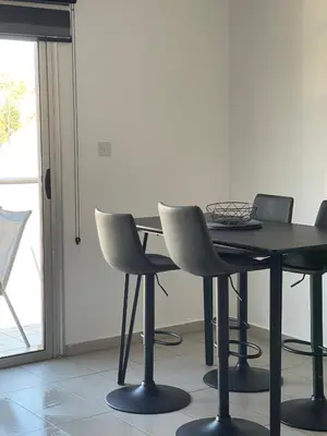 a dining room table with chairs and a black table at Cielo Apartment No2 in Ayia Napa