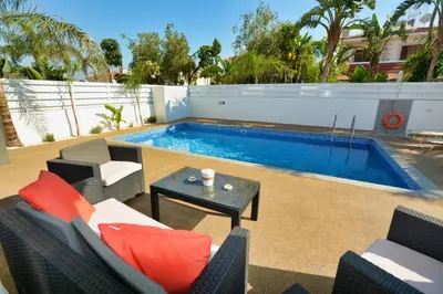 a patio with chairs and a swimming pool at Villa Mario - 2min walk from Kapparis Beach in Paralimni