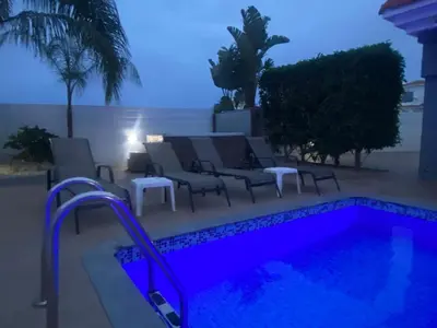 a pool at night with chairs and a table at Villa Mario - 2min walk from Kapparis Beach in Paralimni