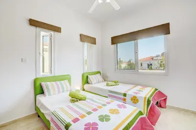 two beds in a room with white walls and windows at Villa Mario - 2min walk from Kapparis Beach in Paralimni
