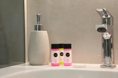a bathroom sink with three bottles of moisturizers on it at Lovely cozy one bedroom suite with pool in Protaras