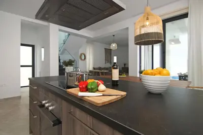 a kitchen counter with a cutting board with vegetables and a bowl of fruit at Villa Queen Isabella in Protaras