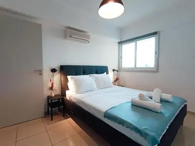 a bedroom with a bed with a blue blanket and a window at The Chalk in Larnaka