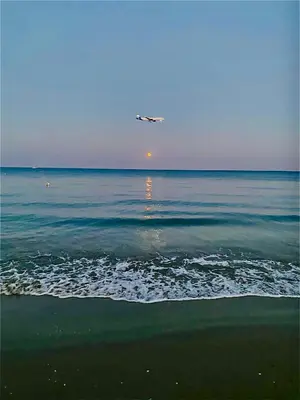 an airplane flying over the ocean with a beach at BALI SUITES 202 in Larnaka
