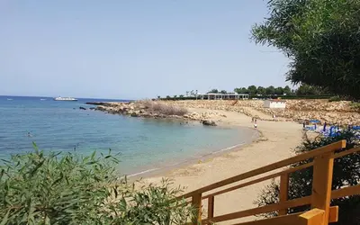 a beach with a wooden fence and the ocean at Villa Queen Eleanor in Protaras