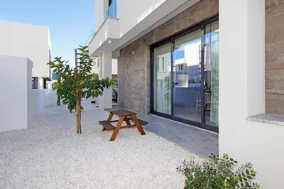 a wooden bench sitting in front of a building at Villa Queen Helena in Protaras