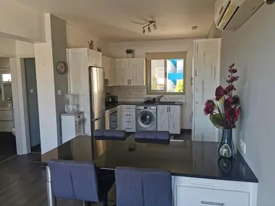 a kitchen with a glass counter top with purple chairs at Sea view cosy apartment in Protaras