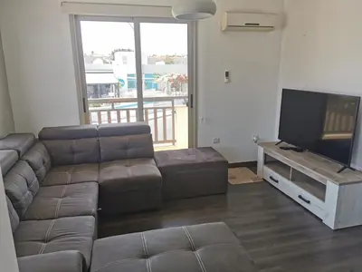 a living room with a couch and a flat screen tv at Sea view cosy apartment in Protaras