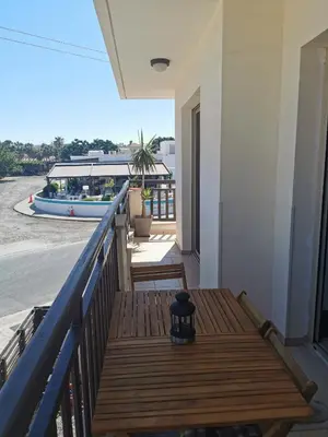 a wooden bench on a balcony with a boat at Sea view cosy apartment in Protaras