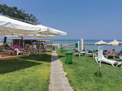 a patio with chairs and umbrellas on the beach at Sea view cosy apartment in Protaras