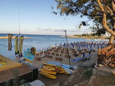 a beach with chairs and umbrellas and the ocean at Sea view cosy apartment in Protaras