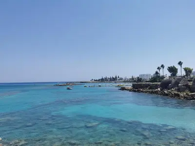 a body of water with a beach and palm trees at Sea view cosy apartment in Protaras