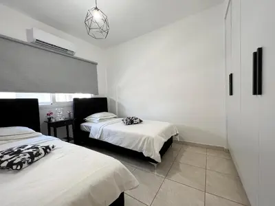 two beds in a room with white walls at Albert's apartment Marina 15 in Larnaka