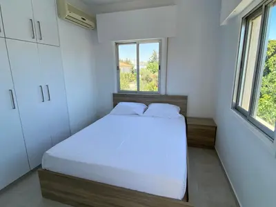 a bedroom with a white bed and two windows at 1-bedroom apartment with view in Limassol