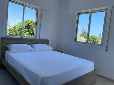 a bedroom with a white bed with two windows at 1-bedroom apartment with view in Limassol