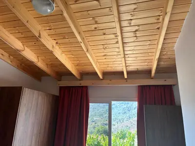 a room with a wooden ceiling with a window at Sofros To Apomero in Ayios Pavlos