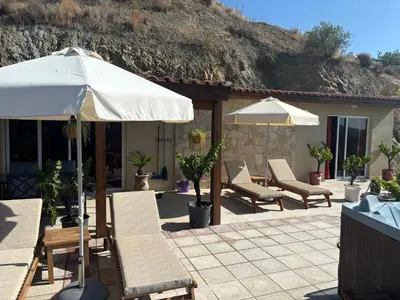 a patio with tables and chairs and an umbrella at Sofros To Apomero in Ayios Pavlos