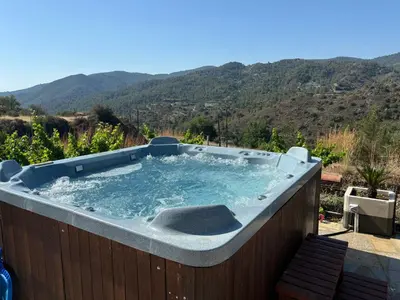 a hot tub with a mountain in the background at Sofros To Apomero in Ayios Pavlos