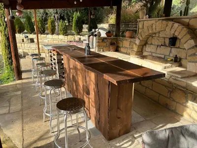an outdoor bar with stools and a stone oven at Sofros To Apomero in Ayios Pavlos