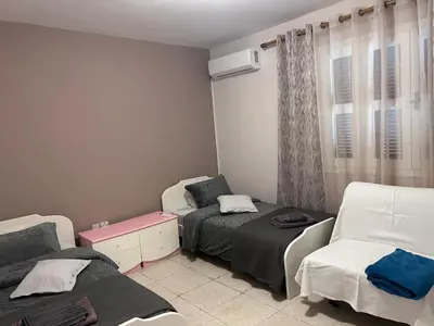 a room with two beds and a couch and a chair at Ptolemaidos cosy Family apartment in Larnaka