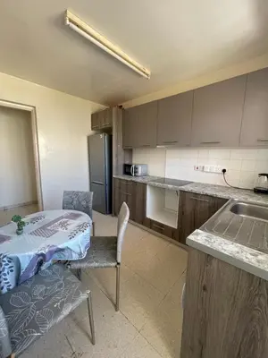 a kitchen with a table and a refrigerator and a table at Ptolemaidos cosy Family apartment in Larnaka