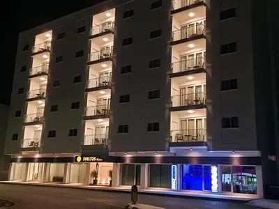 a tall white building with balconies at night at Sveltos Residence Suites in Larnaka
