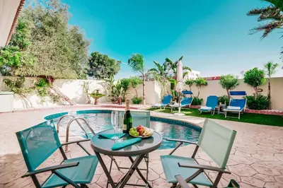 a table with a bottle of wine and chairs next to a pool at Villa Pant Poly in Protaras