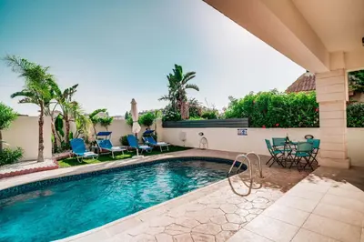 a swimming pool with chairs and a table at Villa Pant Poly in Protaras