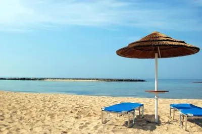 two chairs and an umbrella on the beach at Villa suncity Boutique Beachfront in Ayia Napa