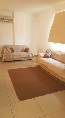 a living room with two beds and a rug at Andris apartment in Paralimni