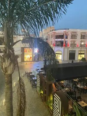 a palm tree and tables and chairs on a city street at 2 bedroom apt in Ermou 4 minute walk beach in Larnaka