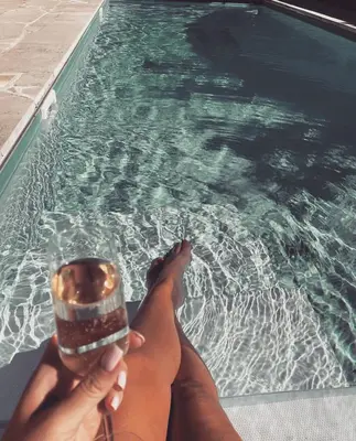 a person holding a drink in front of a swimming pool at Fig&Olive Luxury one bedroom boutique in Pachna in Limassol