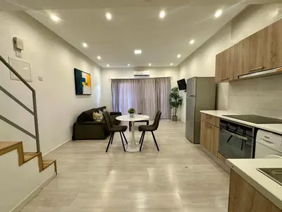 a kitchen and living room with a table and chairs at 1-bedroom duplex 100m by the sea in Limassol