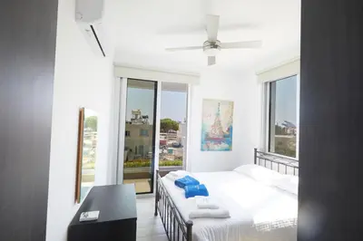 a white bedroom with a bed and a large window at Protaras Pearl Villa Ekaterina in Protaras