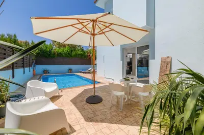a patio with an umbrella and chairs and a pool at Villa Lela Serena by Ezoria Villas in Protaras