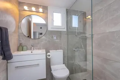 a bathroom with a toilet and a shower and a mirror at White Arches Apt #2 by TrulyCyprus in Limassol