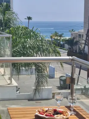 a table with a plate of food and wine glasses on a balcony at Dream Vacation by the Sea Protaras in Protaras
