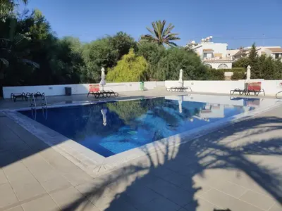a swimming pool with chairs and a person standing next to it at Dream Vacation by the Sea Protaras in Protaras