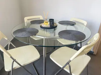 a glass table with chairs and a glass table with a drink on it at High Speed Holiday Apartment in Larnaka