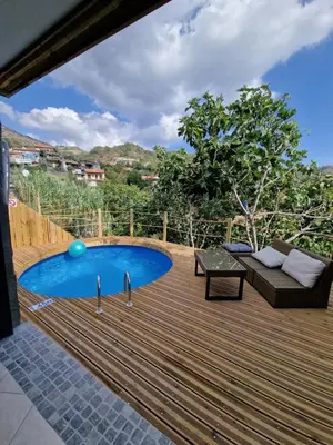 a deck with a pool and a couch and a table at Aprosmeno Jacuzzi House 3 With Private Pool in Agros