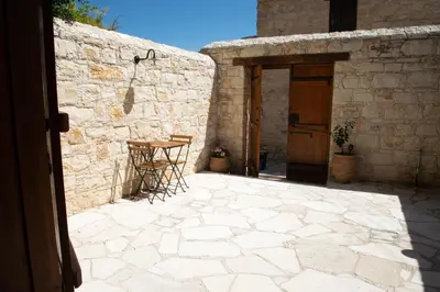 a stone patio with a table and a door at Cleo's Inn in Lofou